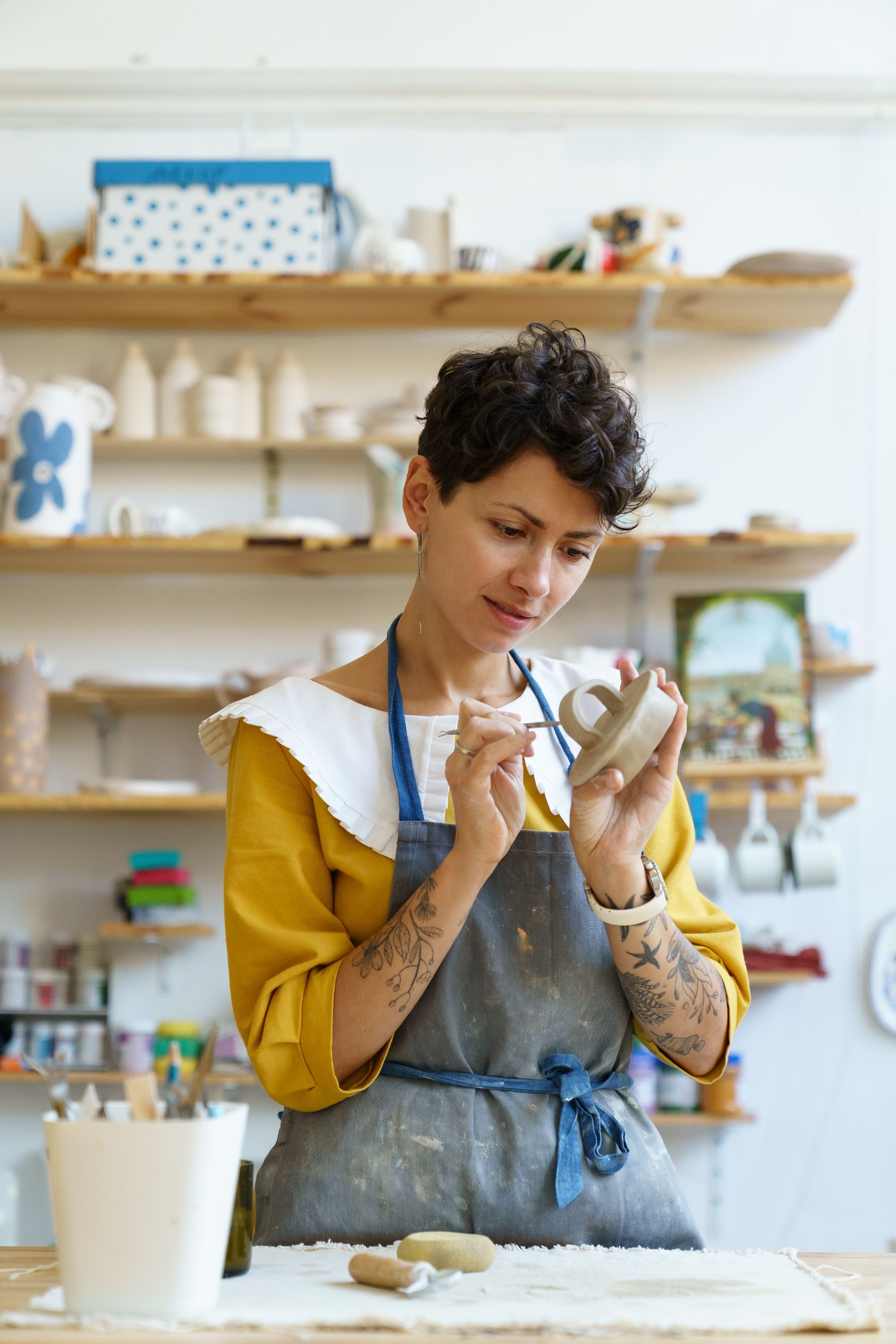 Artisan potter female busy with creative process use tools to decorate mold clay and shape crockery